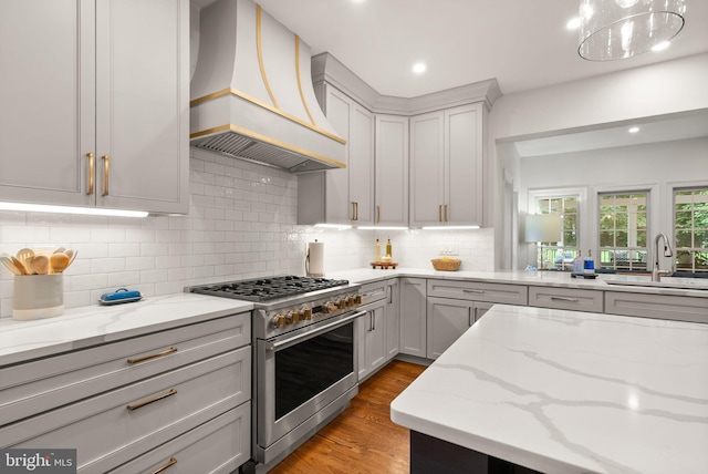 12019 Wandabury Rd, Oakton, VA 22124 - kitchen featuring premium range hood, high end range, a sink, light wood-style flooring, and light stone countertops