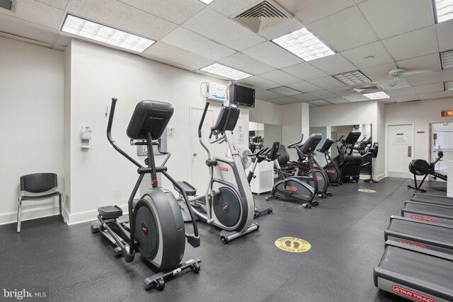exercise room with baseboards and a drop ceiling