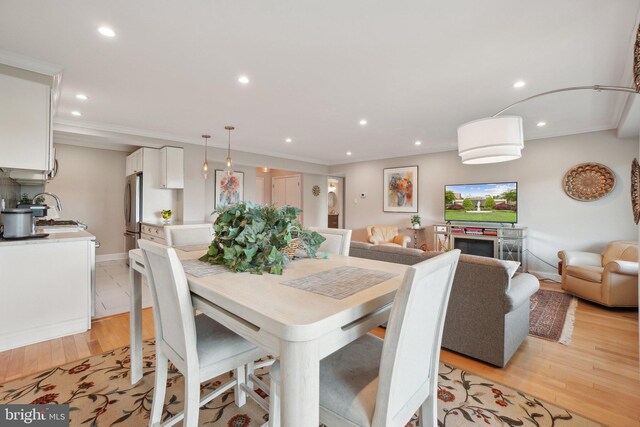 dining room featuring recessed lighting, light wood finished floors, ornamental molding, and baseboards