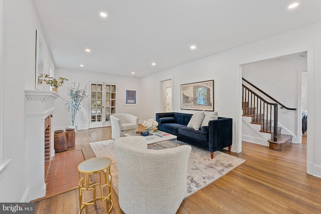 living area featuring stairway, a fireplace, recessed lighting, and wood finished floors