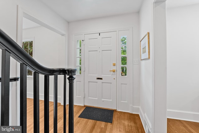 foyer entrance with plenty of natural light, stairs, baseboards, and wood finished floors