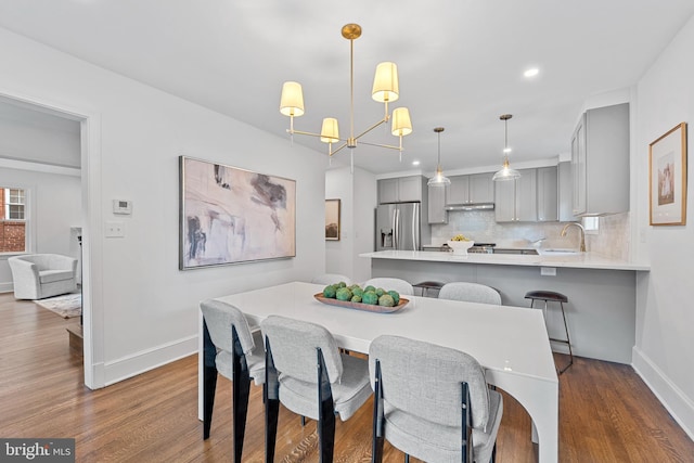 dining space with baseboards, recessed lighting, dark wood-type flooring, and an inviting chandelier