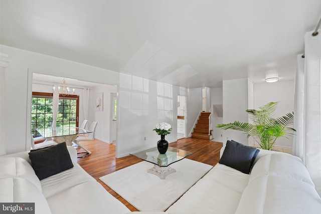 living room featuring a notable chandelier, wood finished floors, and stairway