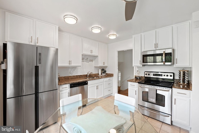 kitchen featuring a sink, light tile patterned flooring, white cabinetry, a ceiling fan, and appliances with stainless steel finishes