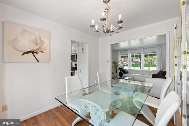 dining area with baseboards, wood finished floors, and a chandelier