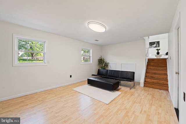 living area with stairway, baseboards, and light wood-type flooring