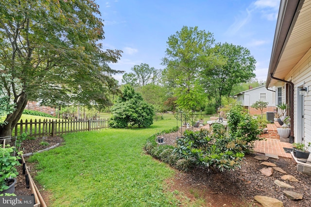 view of yard with fence, a patio, and a garden