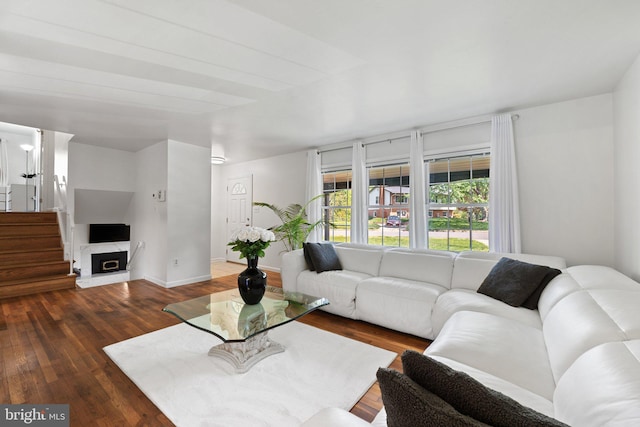 living area with baseboards, wood finished floors, and stairway