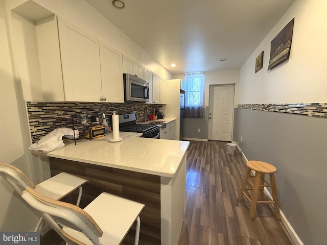 653 N 37th St, Philadelphia, PA 19104 - kitchen featuring backsplash, white cabinets, a peninsula, dark wood-style floors, and stainless steel appliances