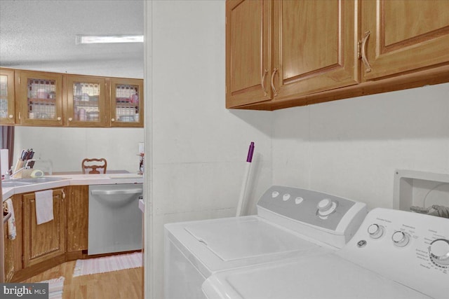 washroom with laundry area, a sink, light wood-style flooring, and independent washer and dryer