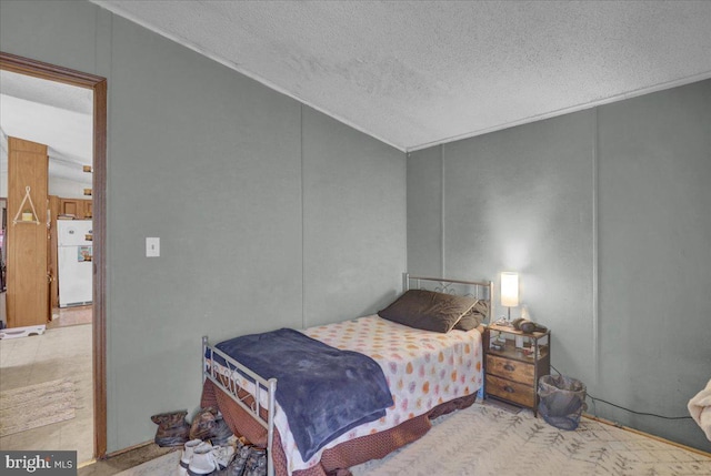 bedroom featuring freestanding refrigerator, a textured ceiling, and vaulted ceiling