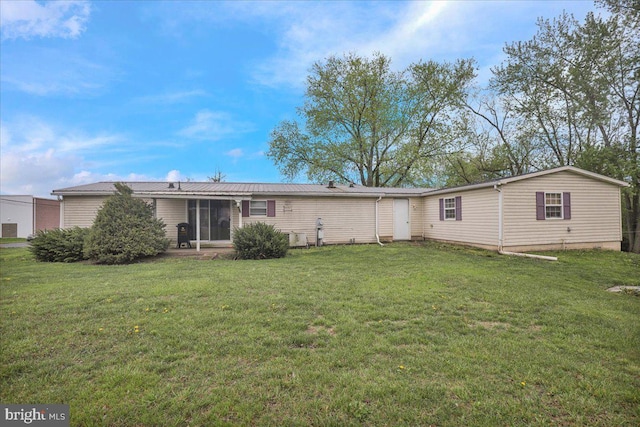 rear view of house featuring a lawn and a sunroom