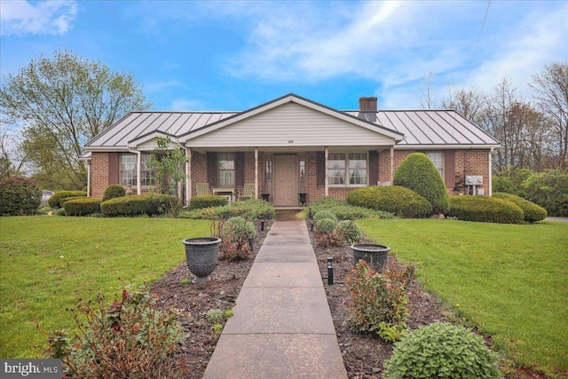 single story home featuring brick siding, a front yard, and a standing seam roof