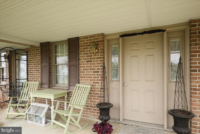 entrance to property featuring a porch and brick siding