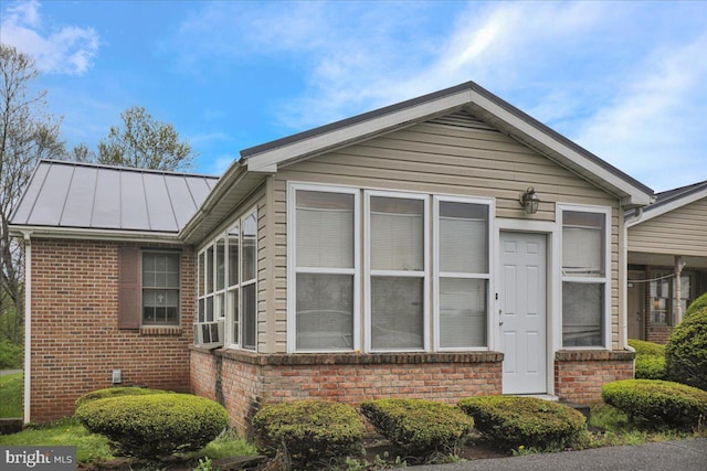 view of property exterior featuring brick siding, metal roof, and a standing seam roof