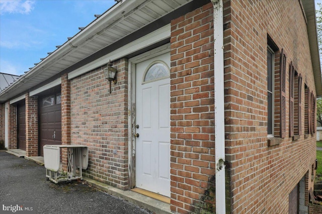 entrance to property featuring brick siding and a garage
