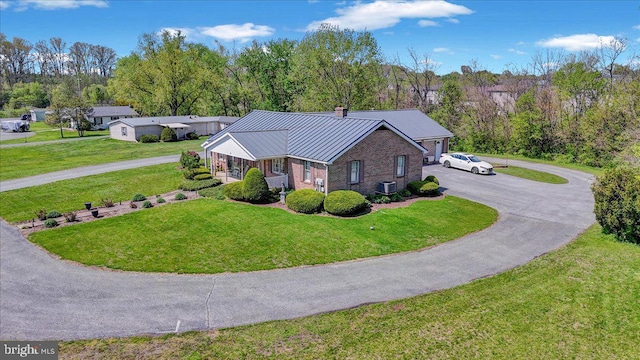 exterior space featuring a standing seam roof, a chimney, a front lawn, and aphalt driveway
