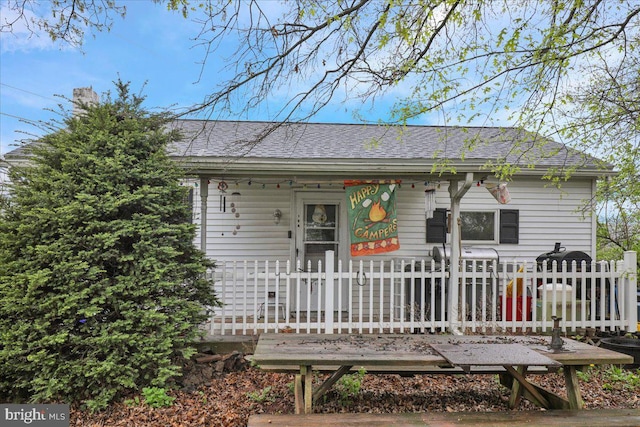 view of front of home with fence, covered porch, and roof with shingles