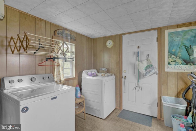 laundry area with laundry area, washing machine and dryer, and wooden walls