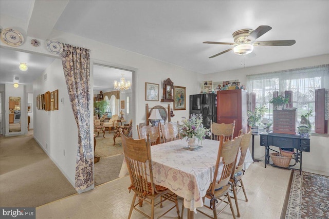 dining room with light colored carpet and ceiling fan with notable chandelier