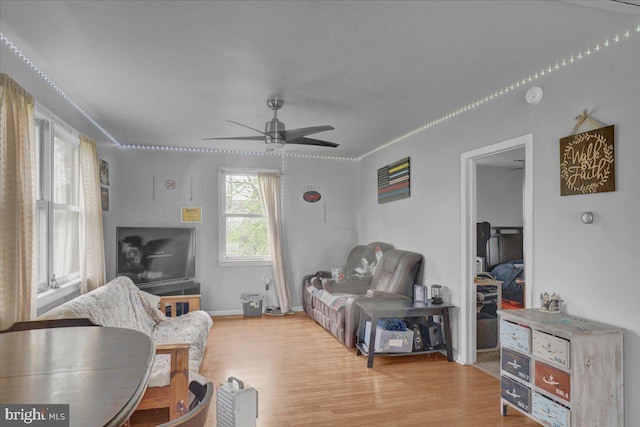 living room with baseboards, light wood finished floors, and ceiling fan