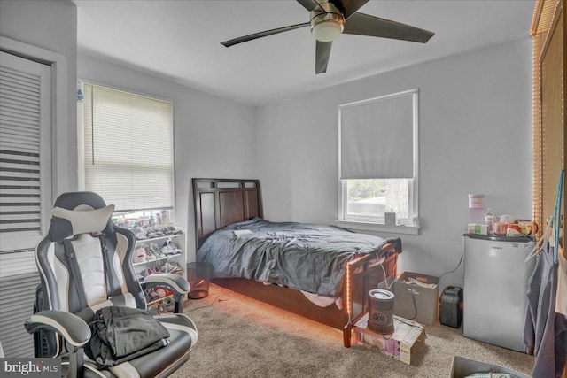 carpeted bedroom with fridge and ceiling fan