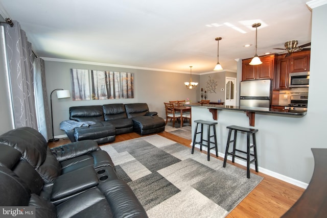 living area featuring crown molding, baseboards, light wood-style flooring, and ceiling fan with notable chandelier