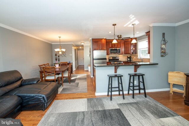 living area featuring an inviting chandelier, baseboards, crown molding, and light wood-type flooring