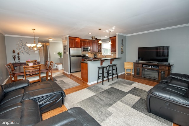 living area featuring crown molding, light wood finished floors, and a notable chandelier