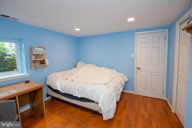 bedroom featuring visible vents, light wood-style floors, and baseboards