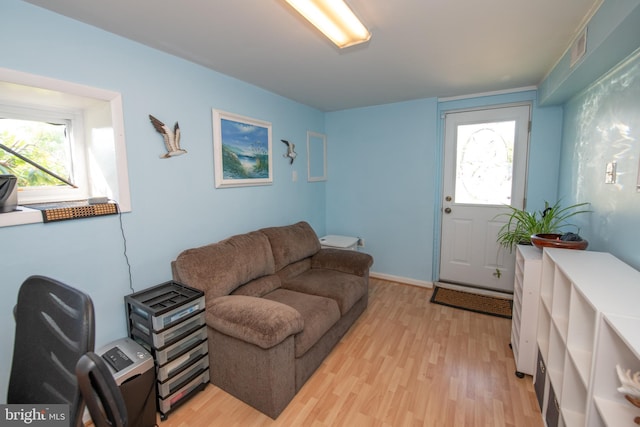 living area with light wood-type flooring, a healthy amount of sunlight, and visible vents