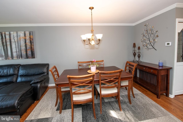 dining area with an inviting chandelier, baseboards, ornamental molding, and wood finished floors