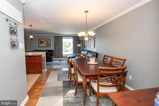 dining space featuring crown molding, light wood-style flooring, baseboards, and a notable chandelier