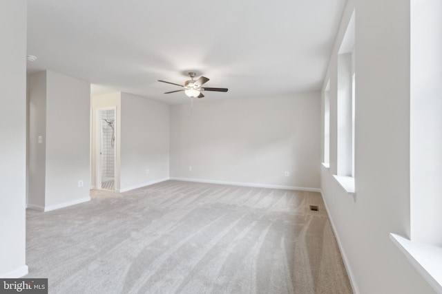 carpeted spare room featuring ceiling fan and baseboards