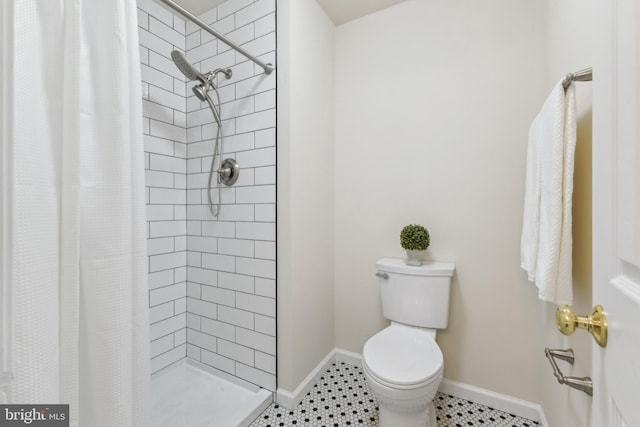 bathroom with a stall shower, toilet, and baseboards