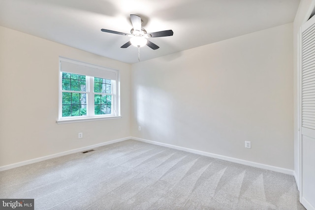 carpeted empty room featuring ceiling fan and baseboards
