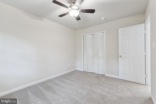 unfurnished bedroom with carpet, a closet, baseboards, and a ceiling fan