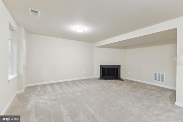 unfurnished living room with carpet floors, a fireplace with flush hearth, and baseboards