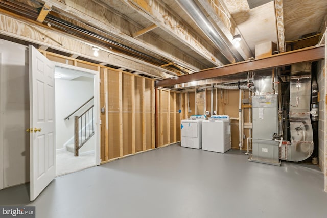 unfinished basement with independent washer and dryer, heating unit, and stairway