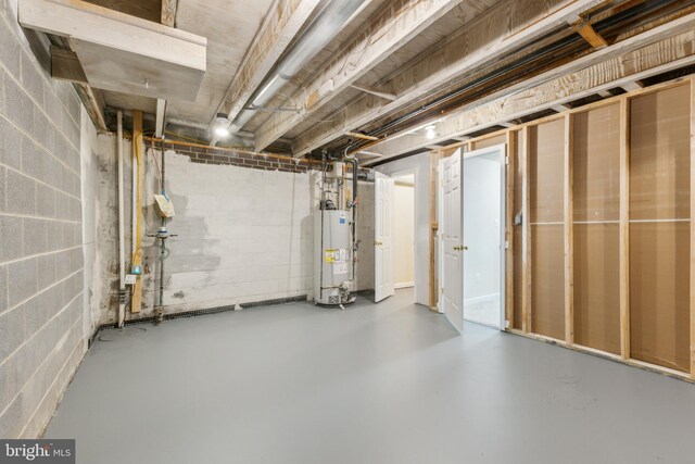 unfinished basement featuring gas water heater and concrete block wall