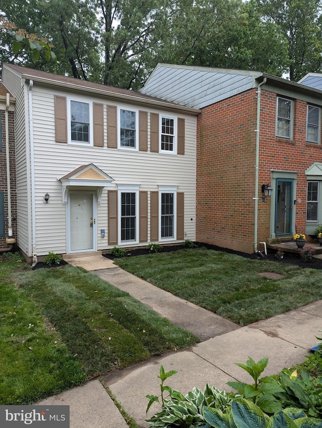 townhome / multi-family property featuring a front yard and brick siding