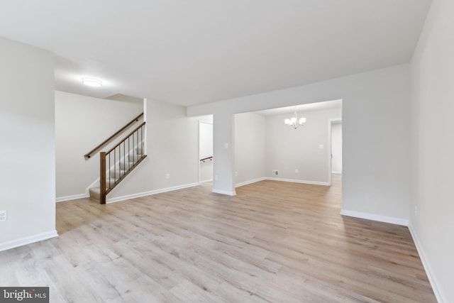 unfurnished living room with a chandelier, stairs, light wood finished floors, and baseboards