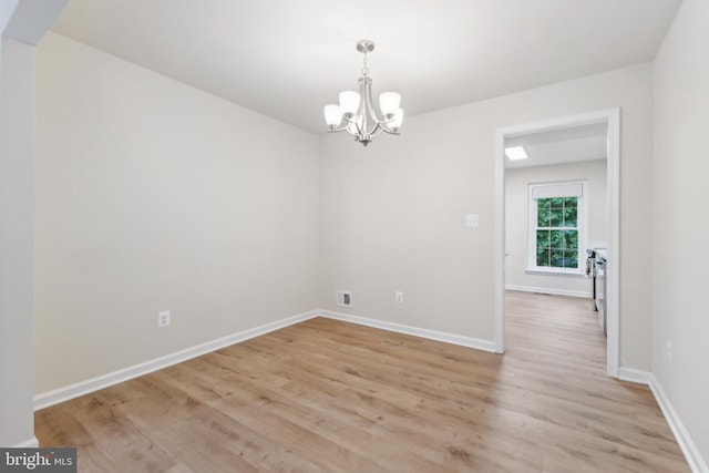 unfurnished room featuring a chandelier, light wood-type flooring, and baseboards