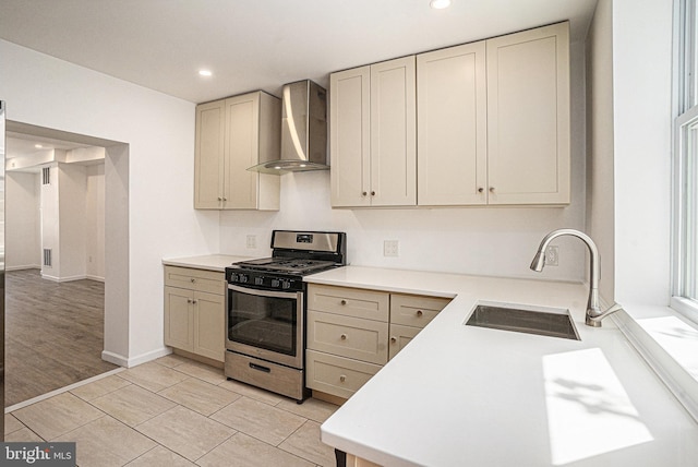 kitchen with wall chimney range hood, stainless steel range with gas stovetop, recessed lighting, and a sink