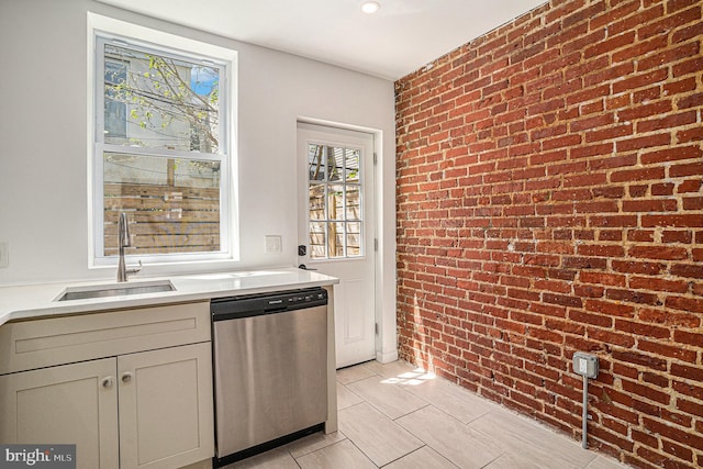 kitchen with light countertops, brick wall, a sink, and dishwasher