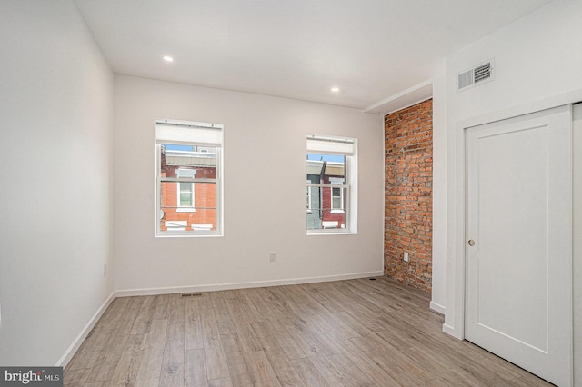unfurnished bedroom featuring light wood-style floors, multiple windows, and visible vents