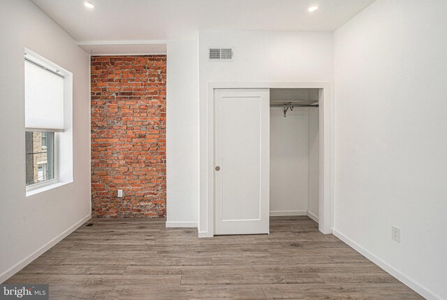 unfurnished bedroom with a closet, recessed lighting, wood finished floors, and visible vents