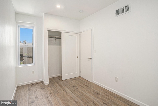 unfurnished bedroom featuring visible vents, baseboards, wood finished floors, and a closet