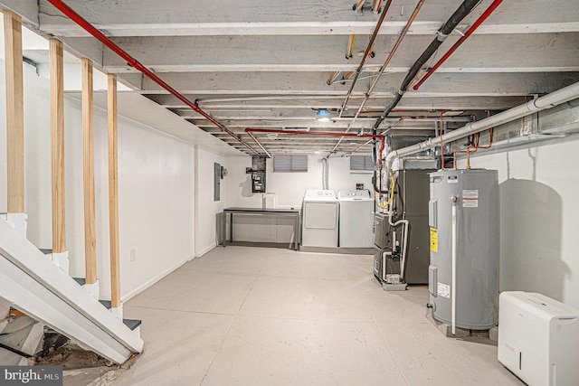 unfinished basement featuring washing machine and clothes dryer, heating unit, electric panel, and electric water heater