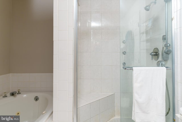 bathroom featuring a tub with jets and a shower stall